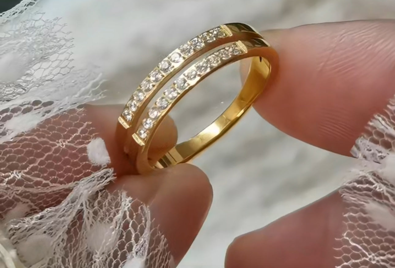 A gold-colored double layer ring with small embedded stones being worn on a finger