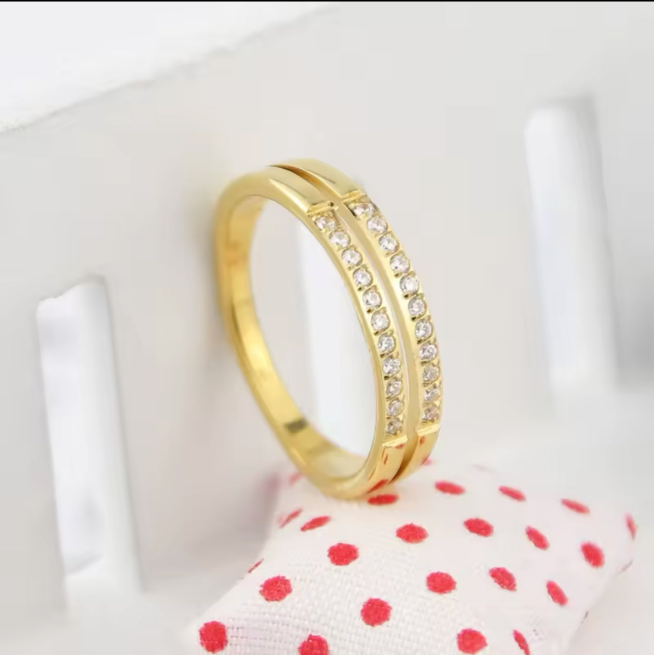 A gold-colored double layer ring with small embedded stones shown on a neutral background