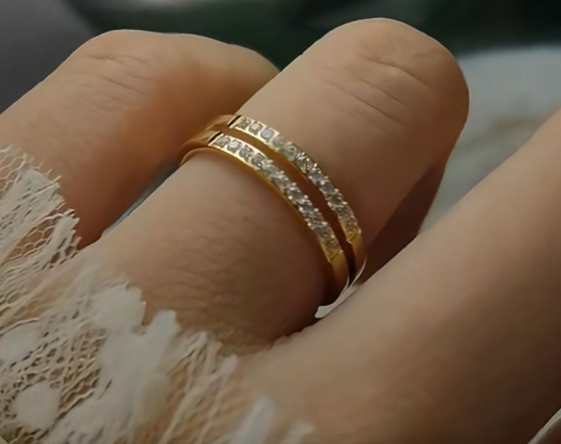 A gold-colored double layer ring with small embedded stones being worn on a finger