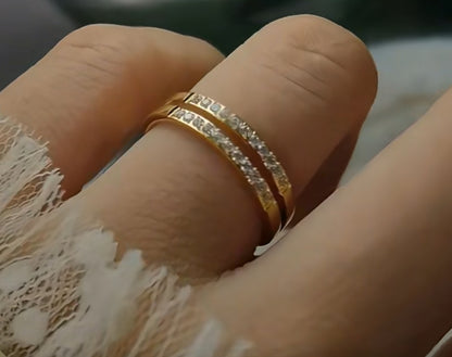 A gold-colored double layer ring with small embedded stones being worn on a finger