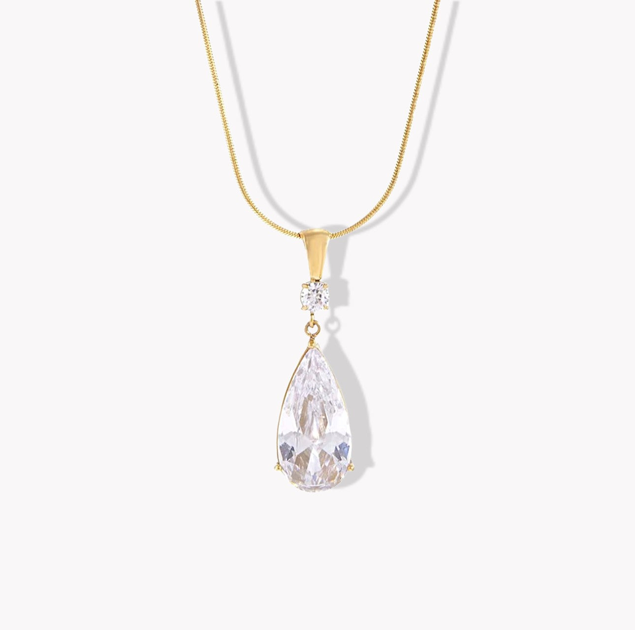 Gold necklace with a teardrop-shaped crystal pendant on a white background