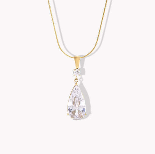 Gold necklace with a teardrop-shaped crystal pendant on a white background