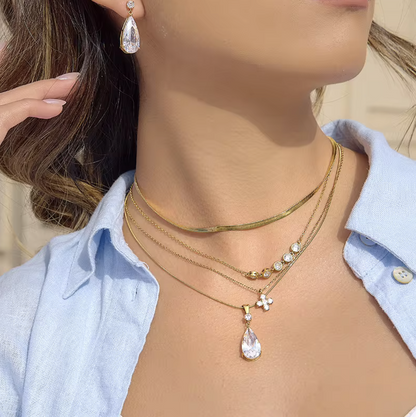 Close-up of a person wearing multiple gold necklaces with teardrop pendants.
