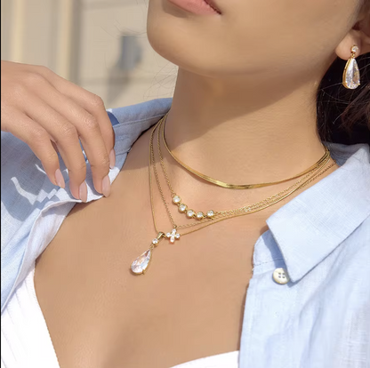 Close-up of a person wearing gold necklaces and earrings with a blurred background