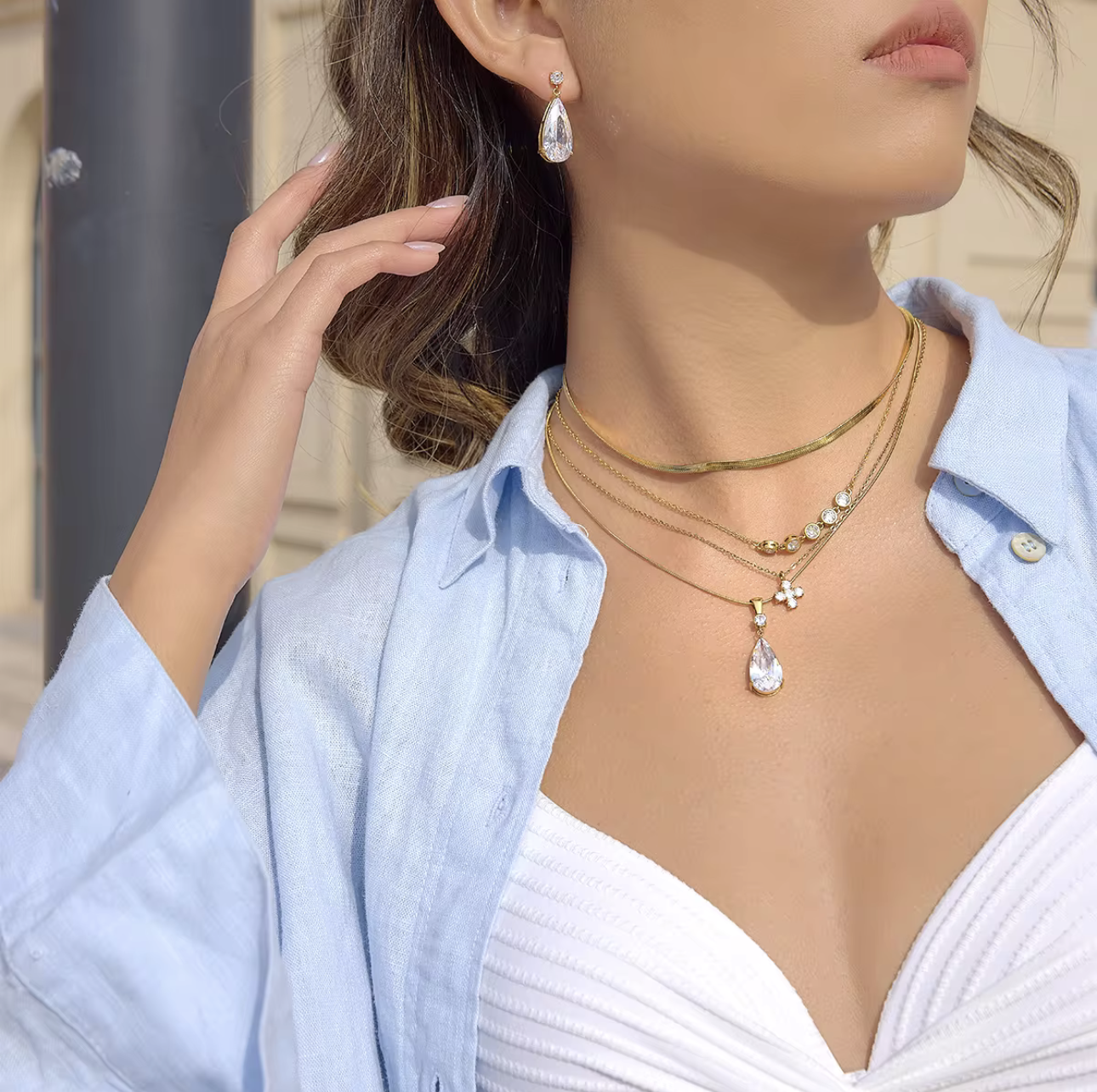 Woman wearing gold necklaces and earrings with a blurred background