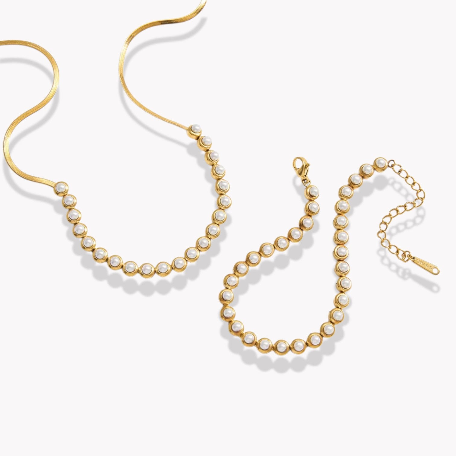 Gold necklace and bracelet with pearl beads on a white background