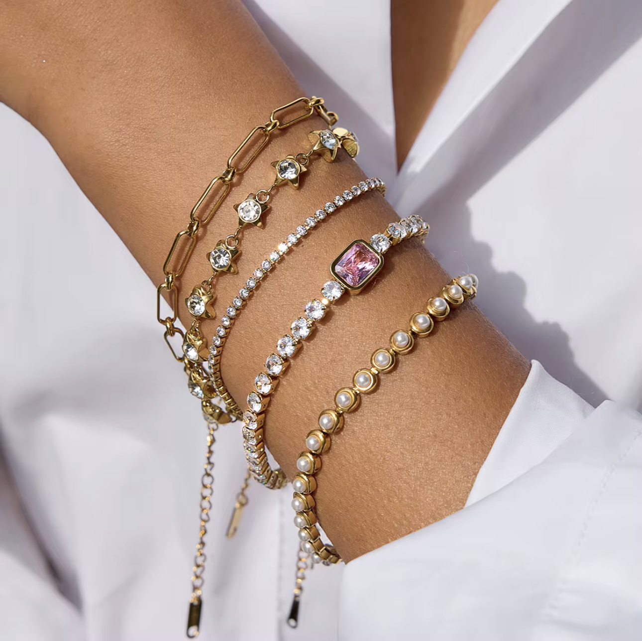 Multiple bracelets with different designs on a wrist against a white background