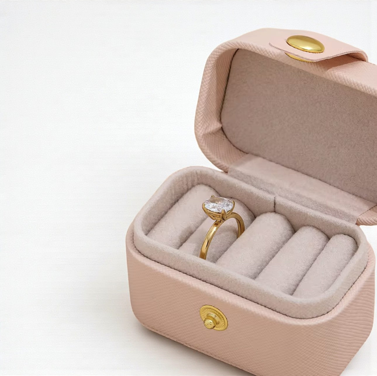 Gold ring with a oval shaped diamond in a pink jewelry box on a white background