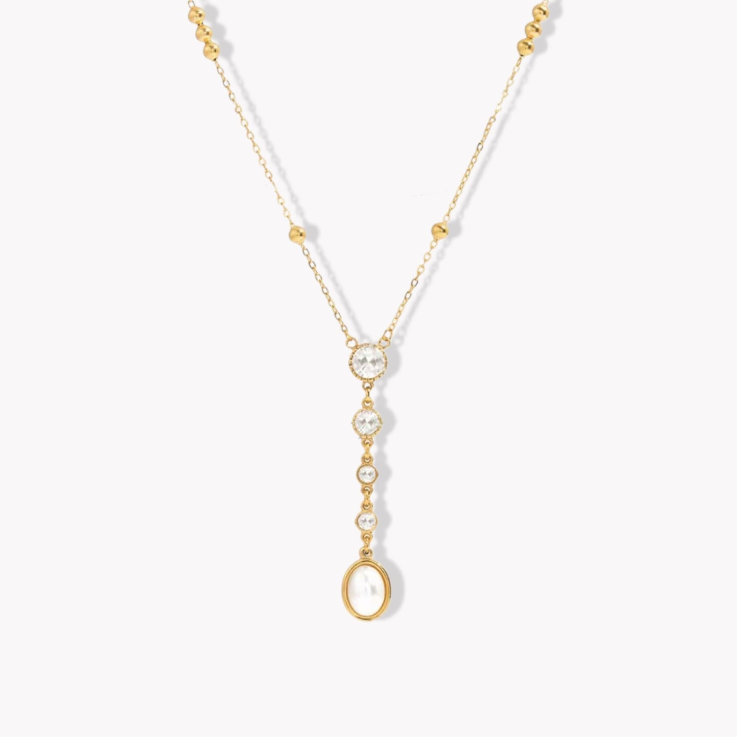 gold necklace with crystal and pearl detail pictured on a light grey background