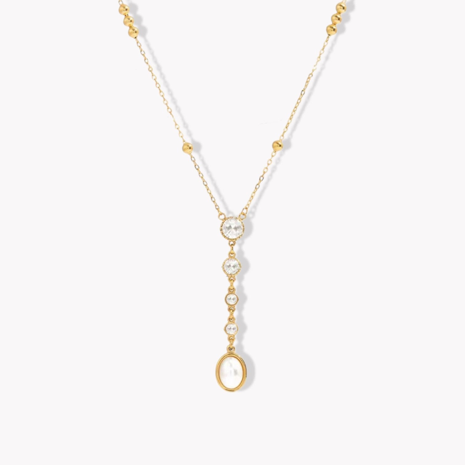 gold necklace with crystal and pearl detail pictured on a light grey background