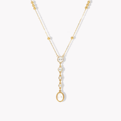 gold necklace with crystal and pearl detail pictured on a light grey background