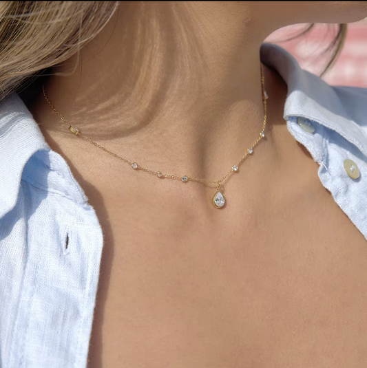 Necklace with a teardrop-shaped pendant worn by a person in a light blue shirt.