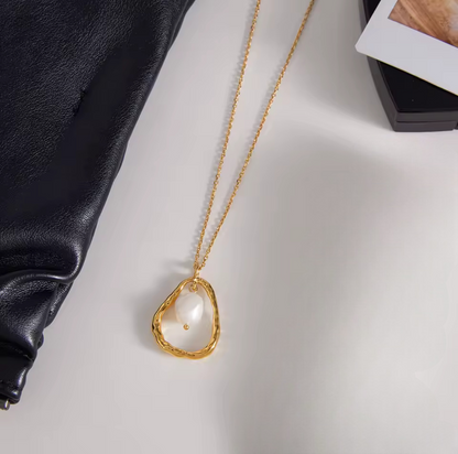 Gold necklace with a pendant on a light gray surface