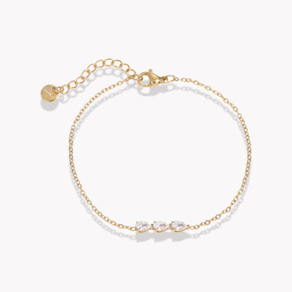 gold dainty bracelet with small pear shaped gemstone detail pictured on a neutral background