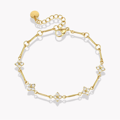 gold bracelet with small flower shaped gemstones pictured on a light grey background