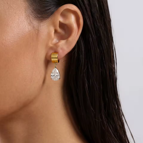 Gold earring with a clear gemstone worn by a person