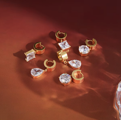 numerous gold earrings with gemstones on a red background