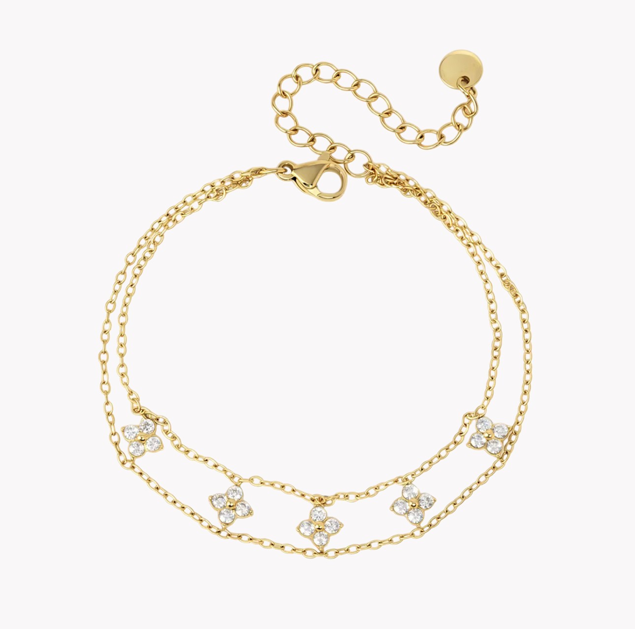 A gold double-strand chain braceletfeaturing five small four-leaf clover motifs paved with clear crystals, shown on a light gray background.