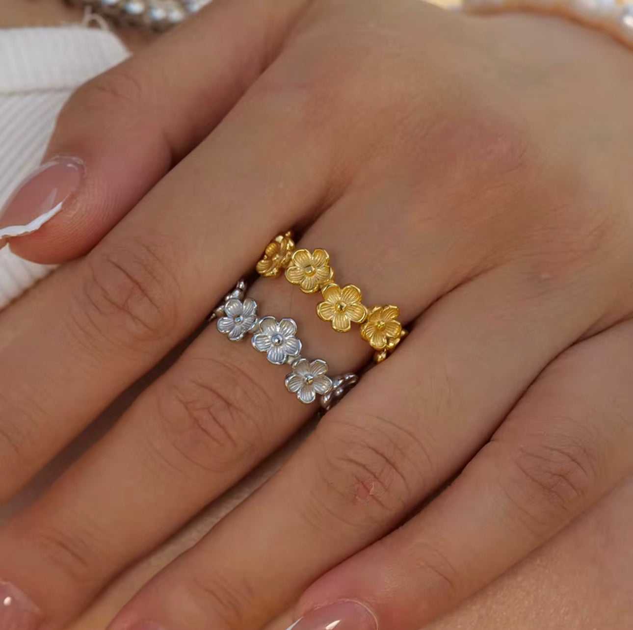gold and silver ring with floral detail being worn on a finger
