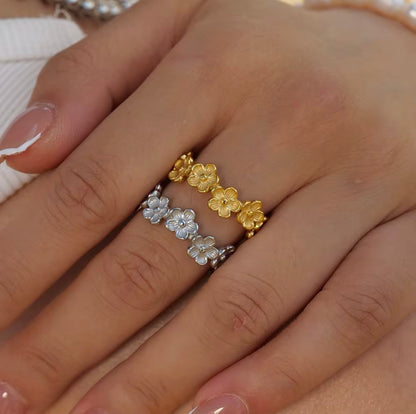 gold and silver ring with floral detail being worn on a finger