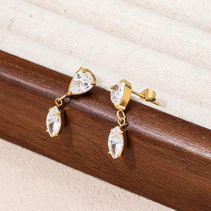 Gold earrings with clear gemstones on a wooden surface