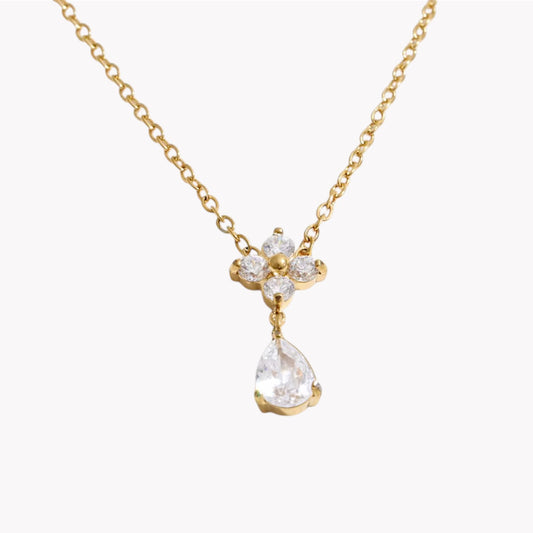 flower shapes gemstone pendant with pear shaped gemstone on a gold necklace pictured on a light grey background
