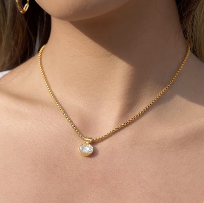Gold necklace with a pendant on a person's neck