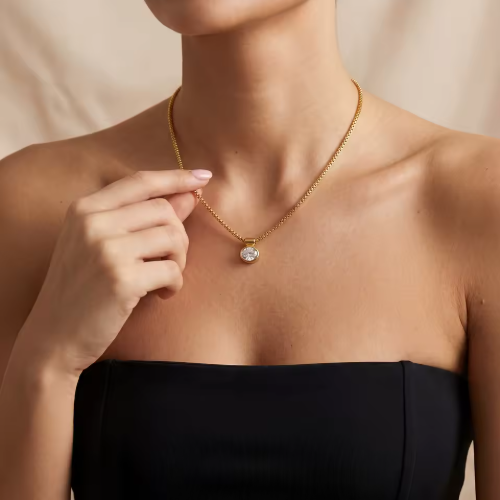 Gold necklace with a pendant worn by a person against a neutral background