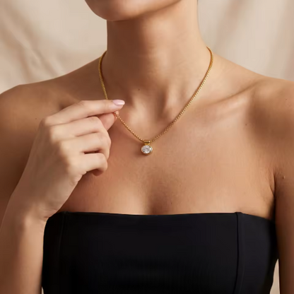 Gold necklace with a pendant worn by a person against a neutral background