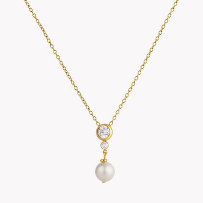 A delicate gold chain necklace featuring a pendant with a round clear stone, a small clear stone, and a dangling white pearl, set against a light gray background.