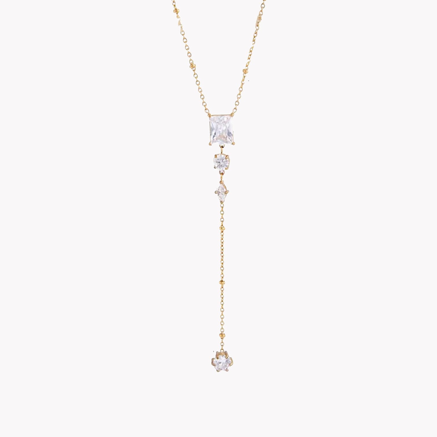 gold necklace featuring clear gemstones of different shapes pictured on a light grey background