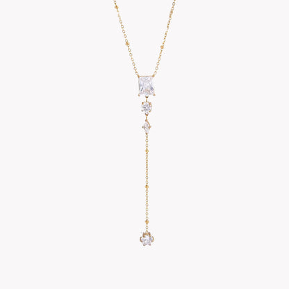 gold necklace featuring clear gemstones of different shapes pictured on a light grey background