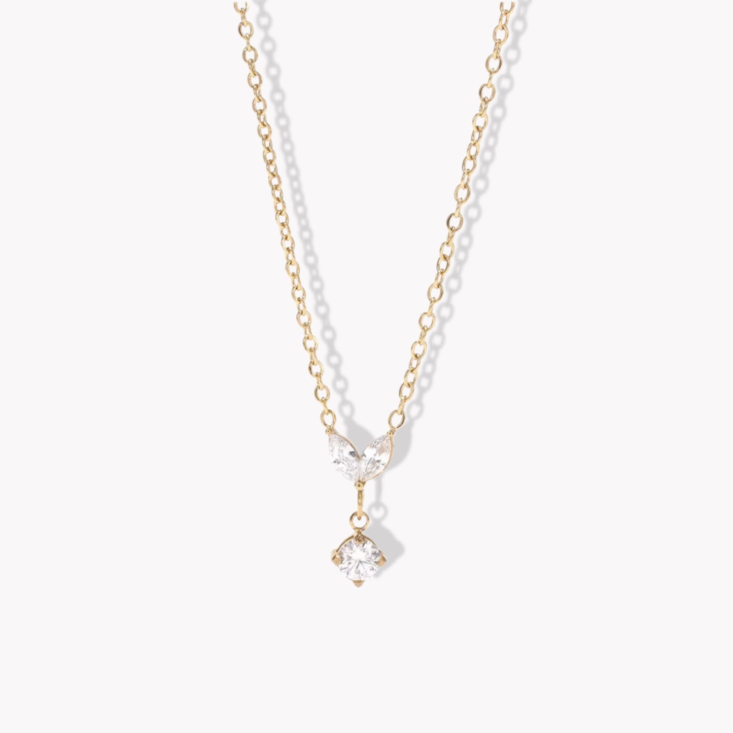 Gold necklace with a clear marquise and round shaped pendant pictured on a white background