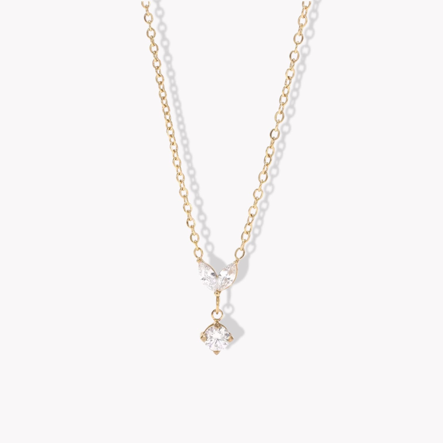 Gold necklace with a clear marquise and round shaped pendant pictured on a white background
