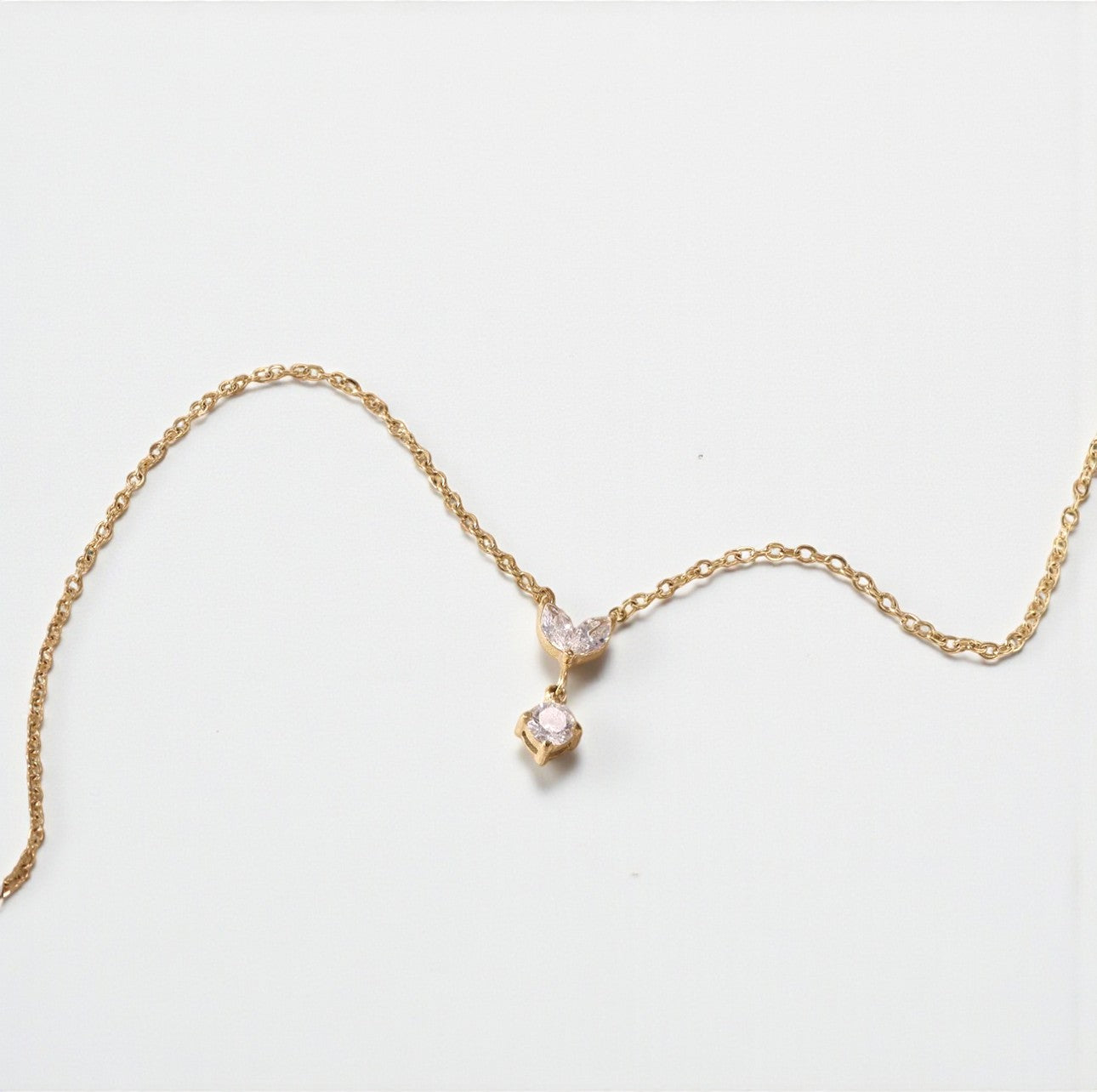 Gold necklace with a clear marquise and round shaped pendant pictured on a white background