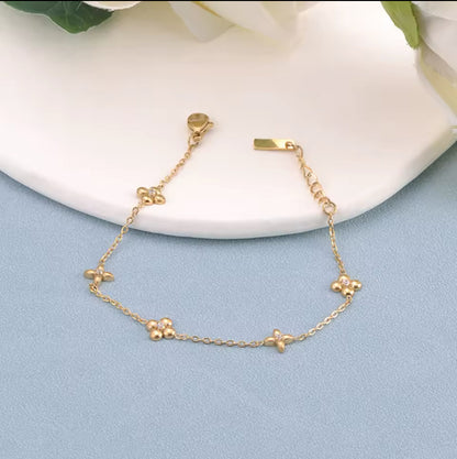 gold bracelet with flower detail on a light blue and white background