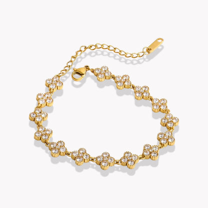 Gold bracelet with clear stones arranged in the shape of a four leaf clover on a white background