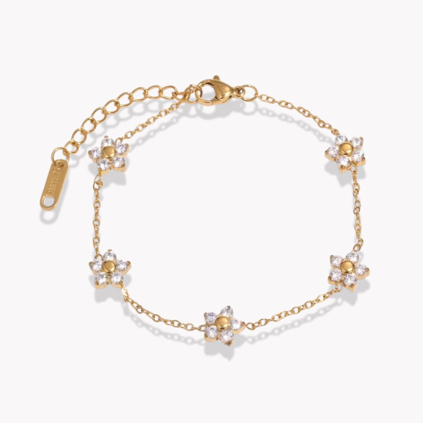 Gold bracelet with clear gemstone floral design on a white background