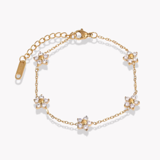 Gold bracelet with clear gemstone floral design on a white background