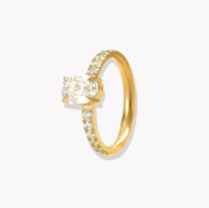 Gold ring with oval gemstone and further gemstones along the band of the ring, pictured on a hand