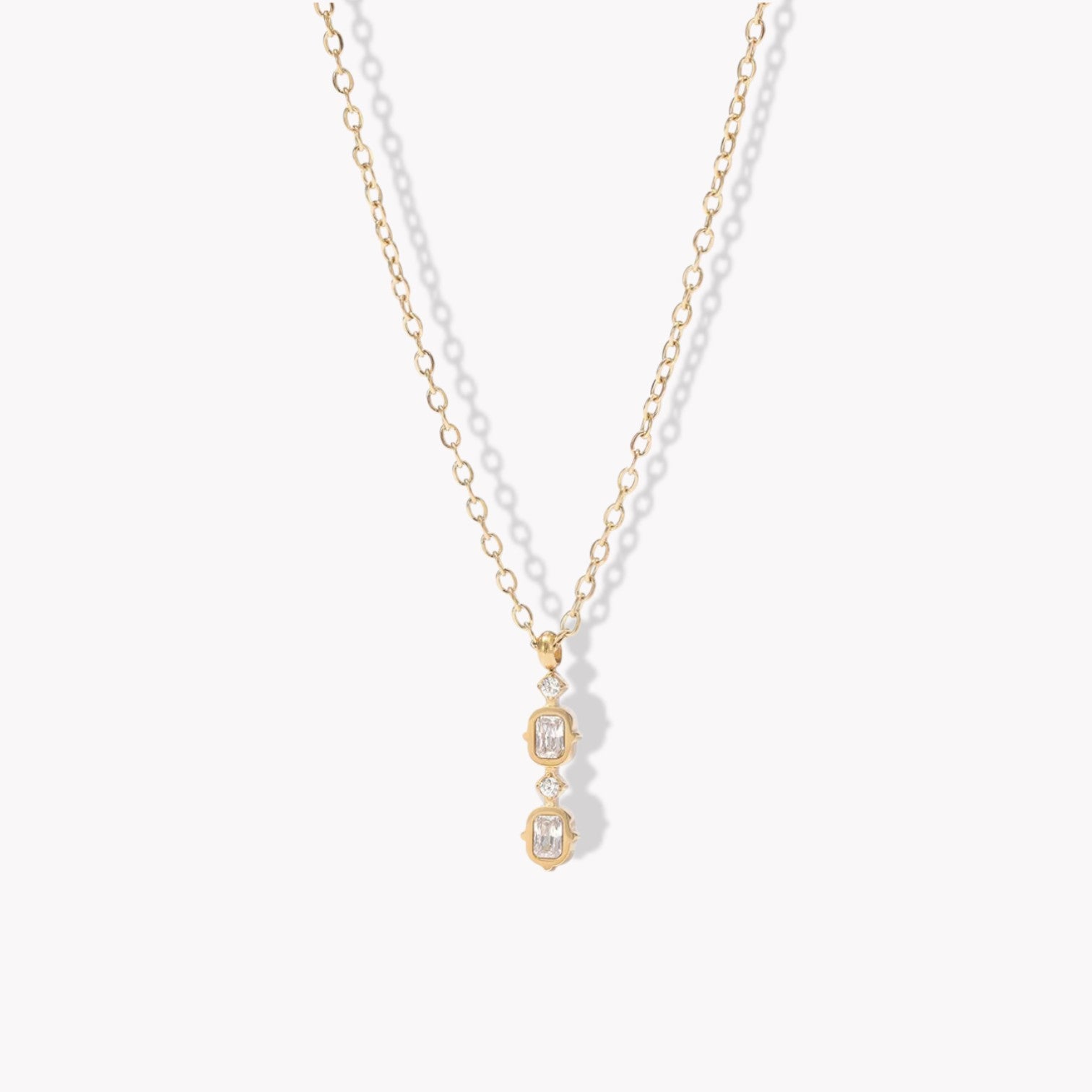 Gold necklace with a clear gemstone pendant on a white background