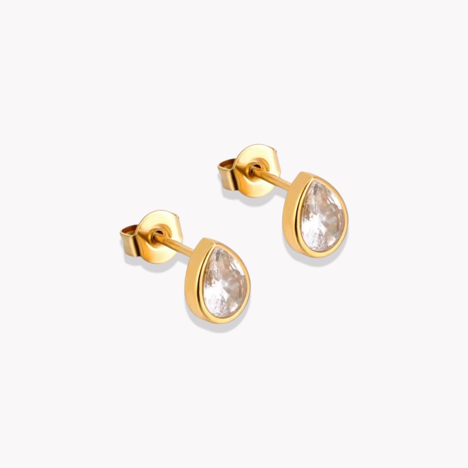 A pair of gold-colored stud earrings with clear pear shaped crystals embedded in them.