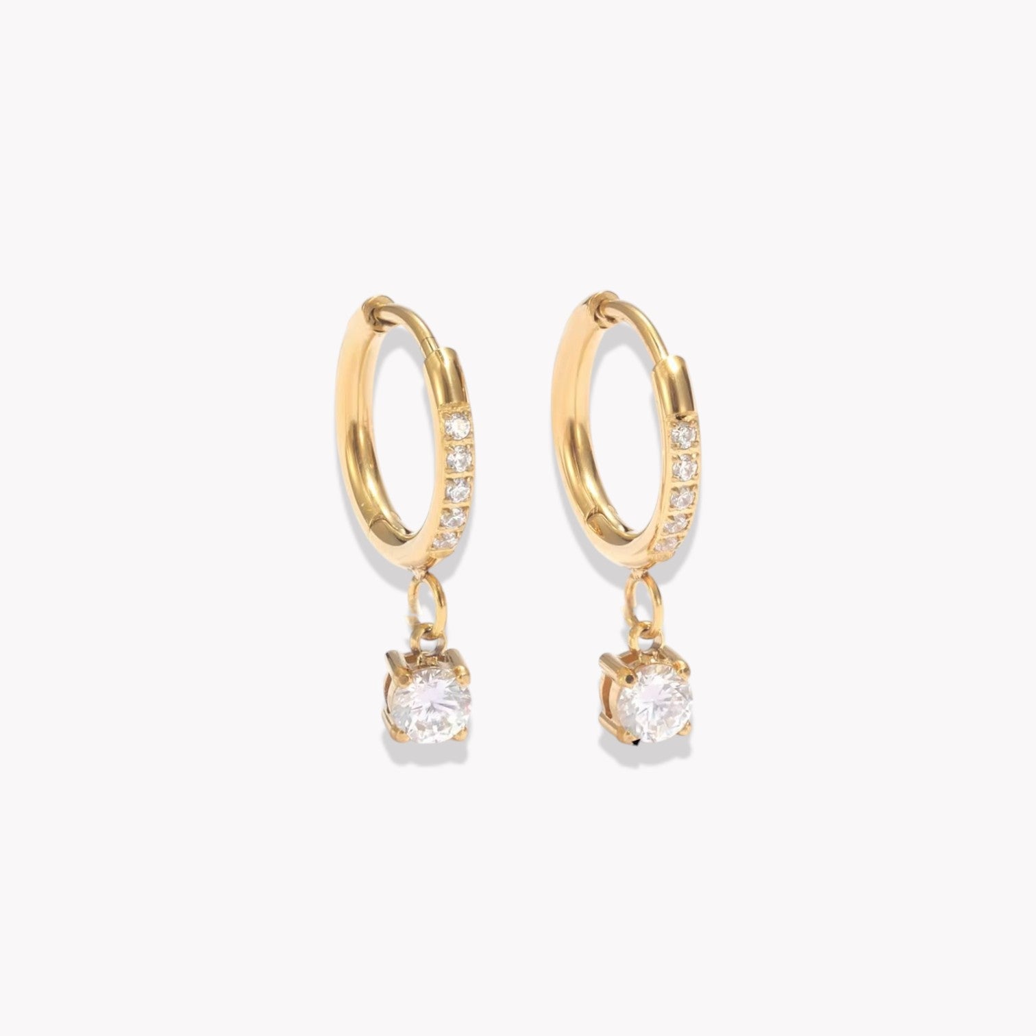 Gold hoop earrings with diamonds on the hoop and a round shaped drop pendant on a white background