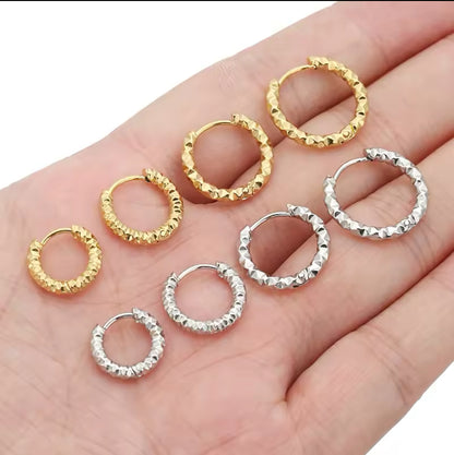four gold and four silver hooped earrings shown on a hand