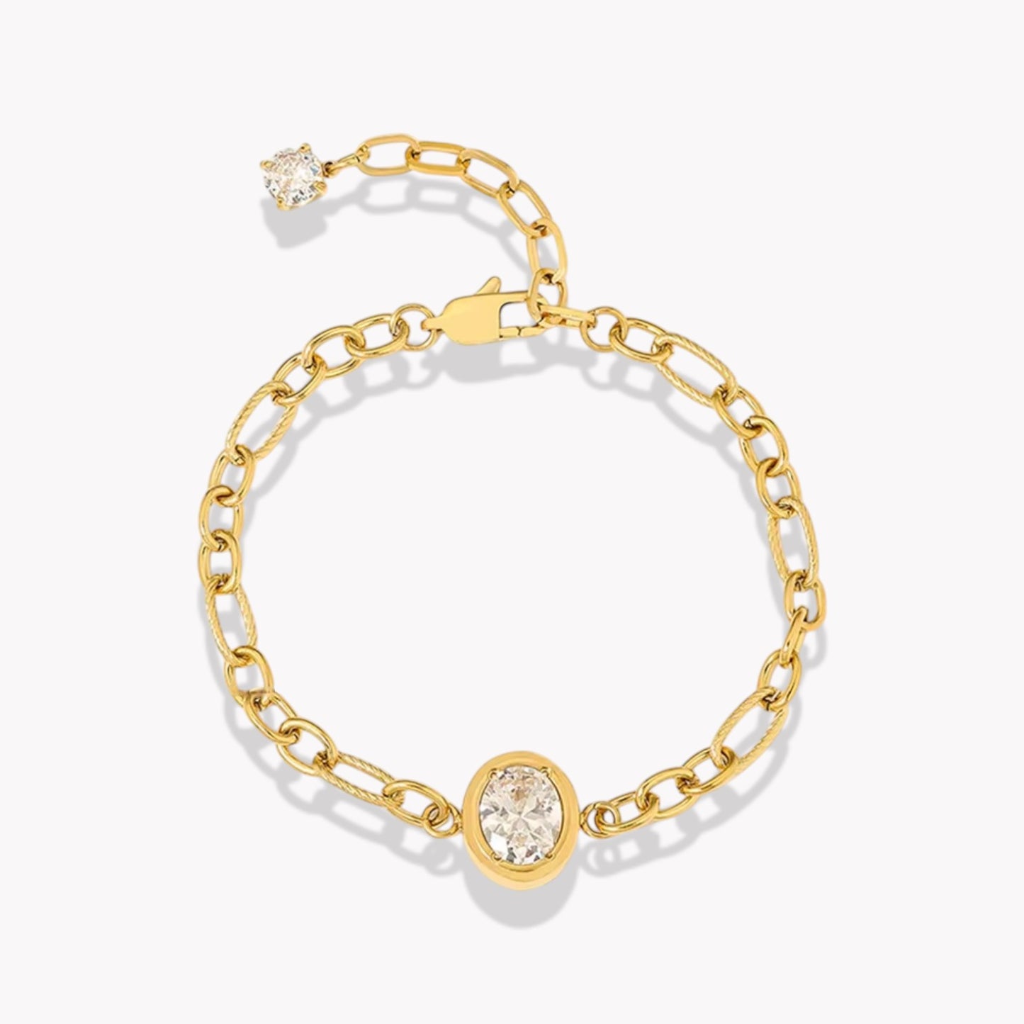 Gold chain bracelet with large central oval diamond. Bracelet has an extender with a clear gemstone on the end. Pictured on a white background