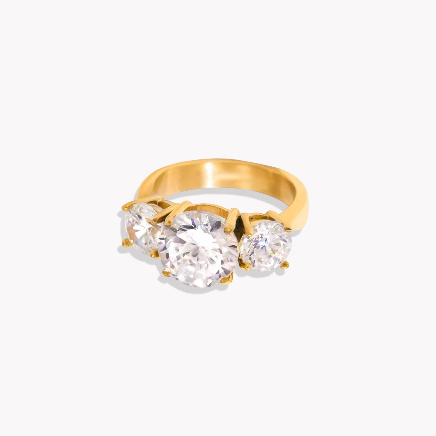 Gold ring with three clear gemstones on a white background