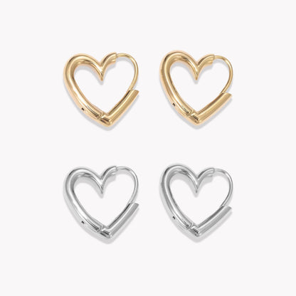 Two pairs of heart-shaped hoop earrings, one gold and one silver, on a white background.