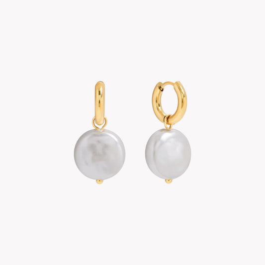 Gold hoop earrings with white pearls on a white background