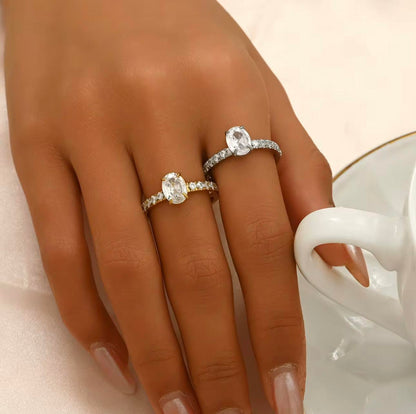 Silver ring with oval gemstone and further gemstones along the band of the ring, pictured on a hand