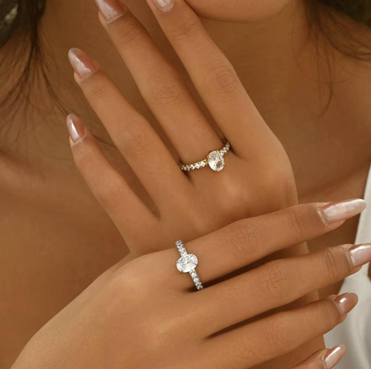 Silver ring with oval gemstone and further gemstones along the band of the ring, pictured on a hand